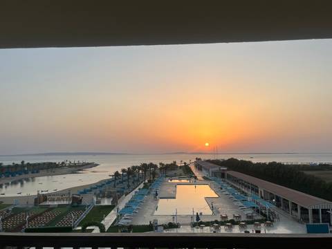       Sunset view over a luxurious waterfront property and pool.
  