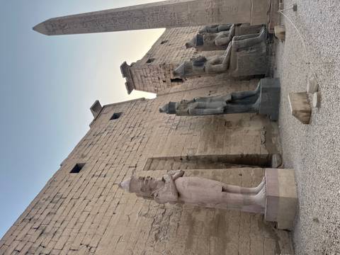       Ancient statues lining a wall near sunset.
  