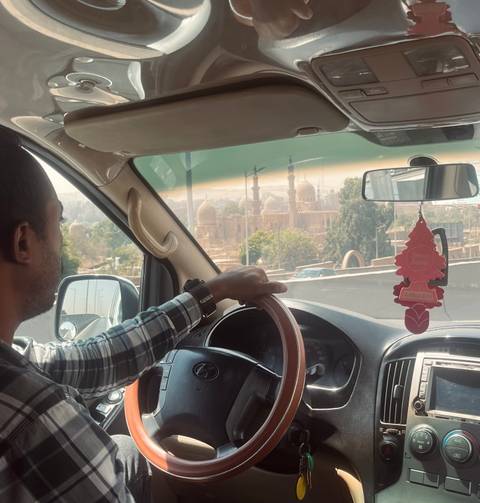       Person driving with city view through the car window.
  