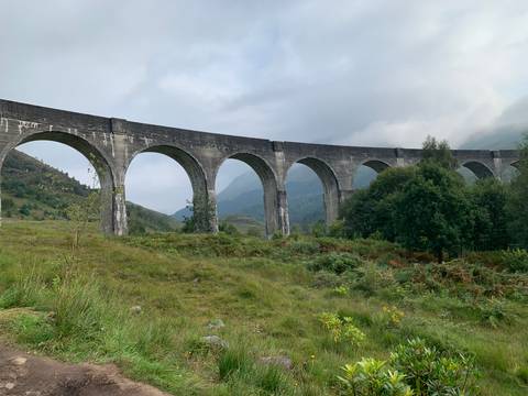 The Glenfinnan Viaduct arches over a lush landscape with mountains in the background.