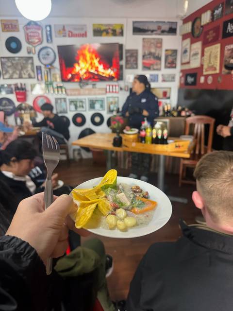       A person holding a plate of food in a room with other people and decor.
  