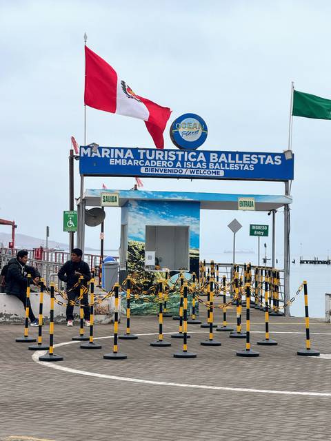       Entrance to Marina Turistica Ballestas with people and signage.
  