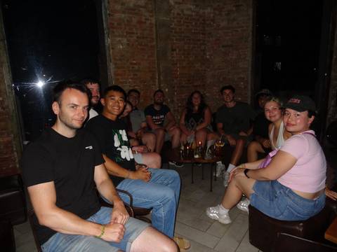       Group of people sitting together in a dimly lit room with drinks.
  
