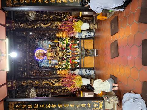 Buddhist shrine with floral decorations and worshippers.