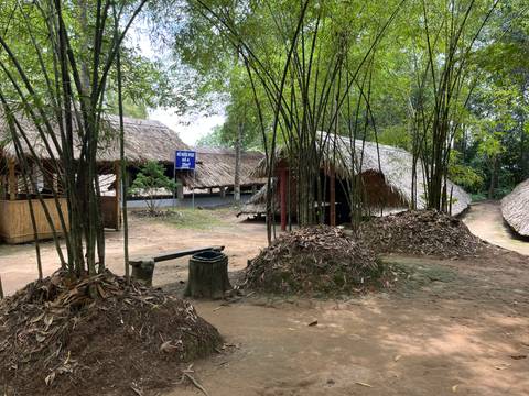Traditional huts with thatched roofs among bamboo and leaf piles.