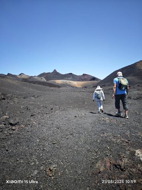       Two people hiking on a volcanic landscape.
  