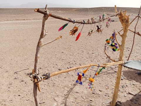 Colorful handcrafted trinkets hanging on a wooden frame.
