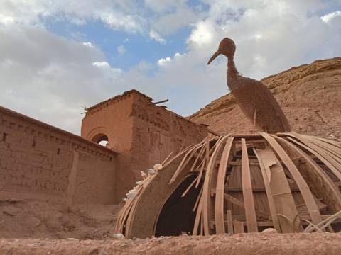       Artistic sculpture on a mud-brick rooftop with sky in the background.
  