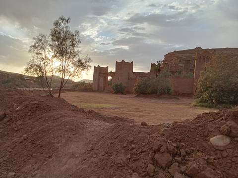       Fortified clay village with cloudy sky at sunset.
  