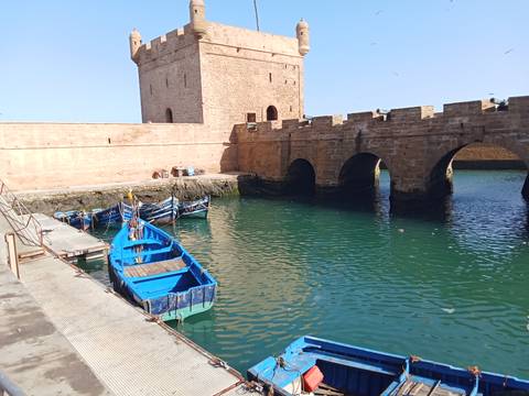 Stone fortress walls and moat with blue boats.