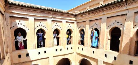 People exploring an old building with arched windows.