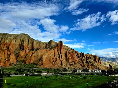       Distinctive red cliffs with a blue sky and few clouds.
  