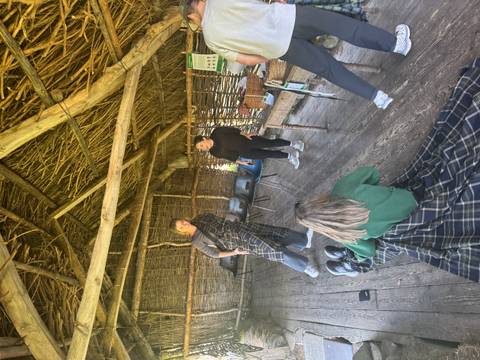 People inside a rustic hut, wearing traditional Scottish attire.