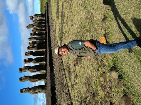 Person posing in front of a line of Moai statues.