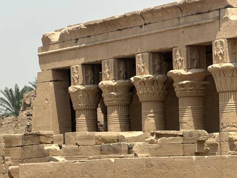 Ancient columns with intricate carvings outside a temple.