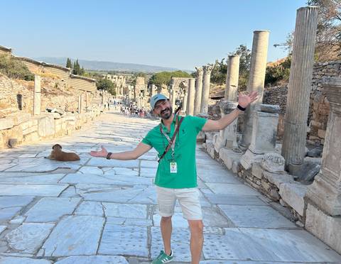 Person posing on ancient street with ruins in the background.