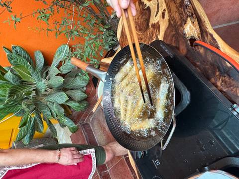 Frying pan with spring rolls cooking in oil.