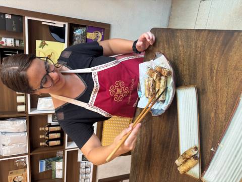 Person preparing spring rolls on a plate.
