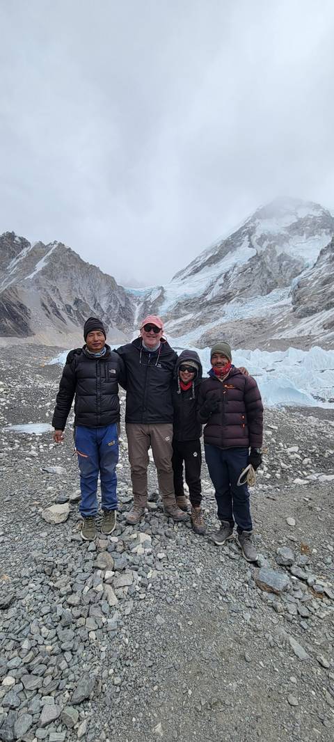 Four people posing at a snowy mountain base camp.