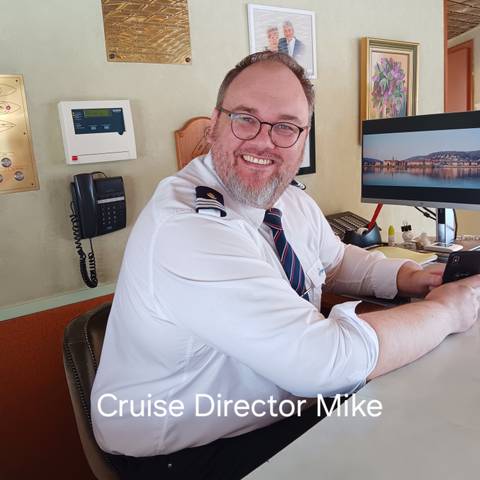 A person smiling at the camera with a computer in the background.