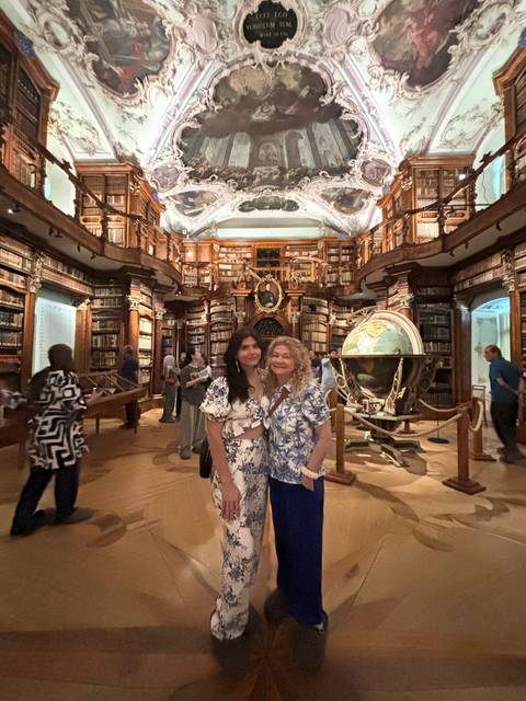 Two people posing inside an ornate library.