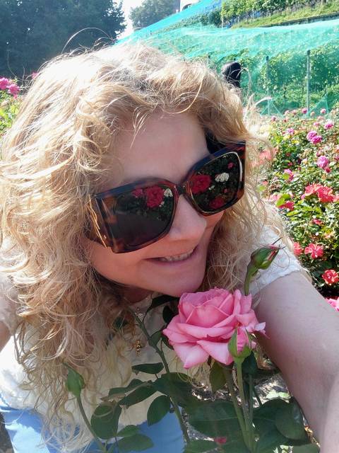Person holding a pink rose, surrounded by flowers.