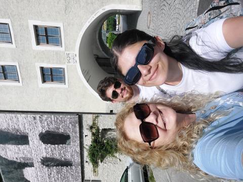 A group of three people smiling outdoors.