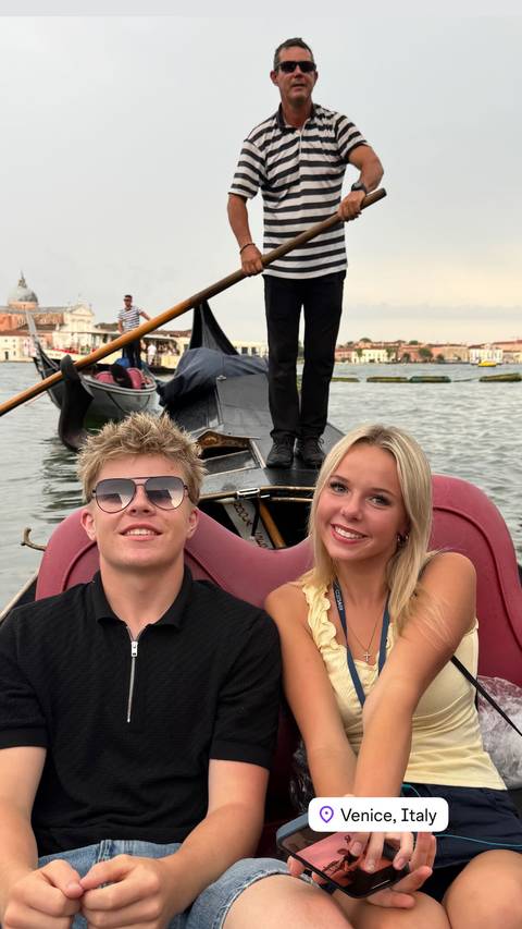       Two smiling people on a gondola in Venice.
  