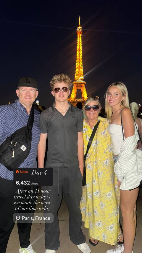 A family posing at night with the lit Eiffel Tower in the background.