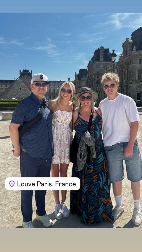       Family posing outdoors under sunny conditions.
  