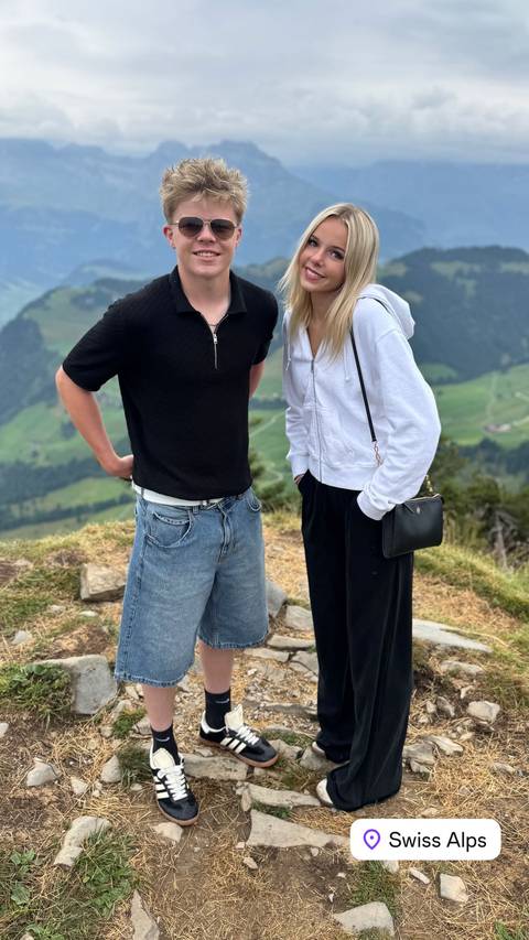 Two people on top of a green landscape with mountains.