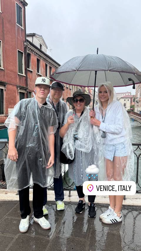 Family wearing rain ponchos posing on a bridge.
