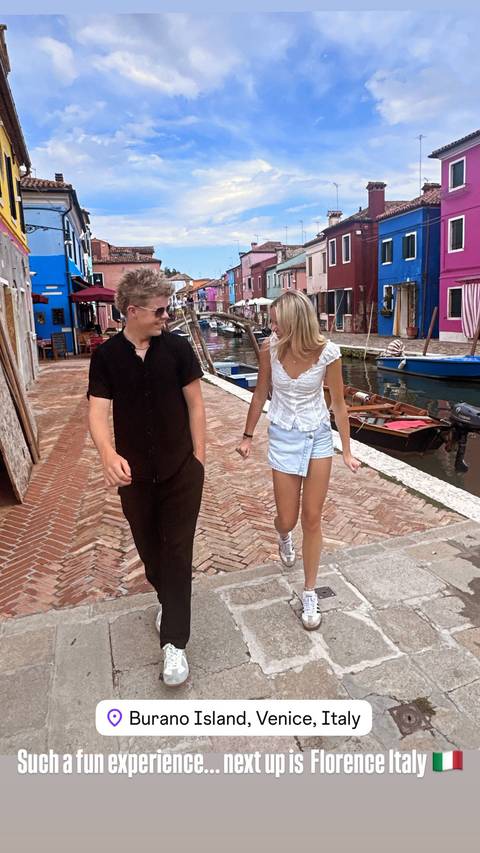       Two people walking in a vibrant street with a canal.
  