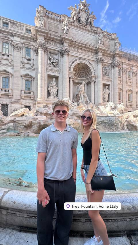 Two people posing in front of the Trevi Fountain.
