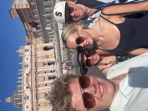       Family posing in front of St. Peter's Basilica on a sunny day.
  