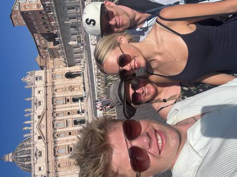 Family posing in front of St. Peter's Basilica on a sunny day.