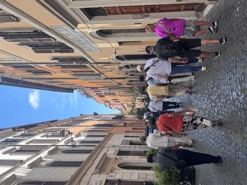       Cobbled street lined with old buildings and a group of people walking.
  