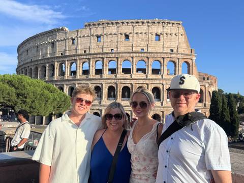 A group of four people in front of the Colosseum.