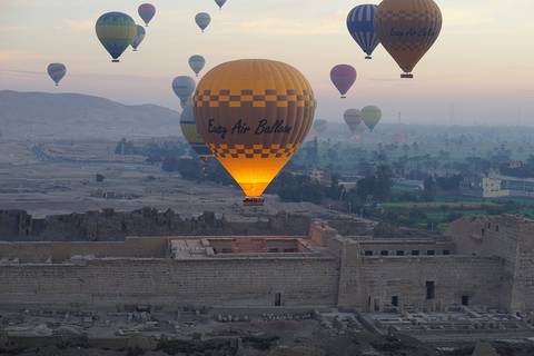 Hot air balloons in the sky at sunrise over ancient ruins.