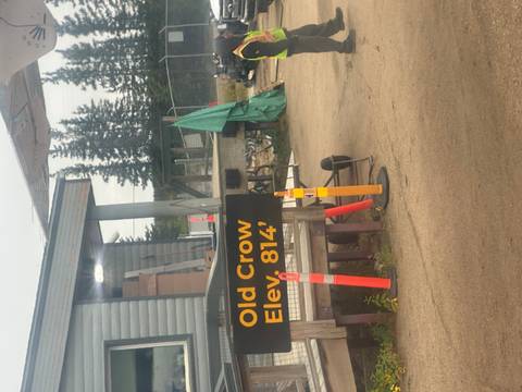       A sign for Old Crow with surrounding rural airport scenery.
  
