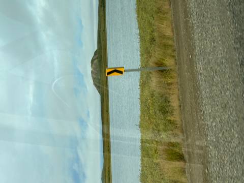       Blurred image of a road sign and a distant hill across a body of water.
  