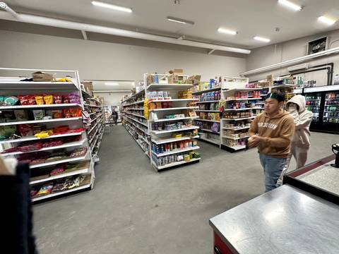       Inside view of a grocery store with people walking through the aisles.
  