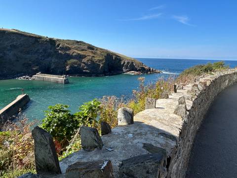 Picturesque coastal scene with vibrant blue water and rugged cliffs under a clear sky.