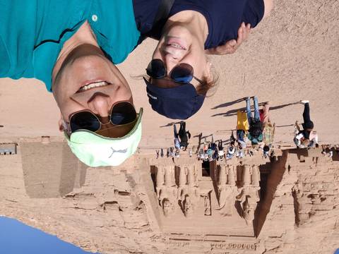 Two people taking a selfie in front of Abu Simbel temples with others in the background.