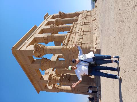 Two people posing in front of ancient columns at a temple site.