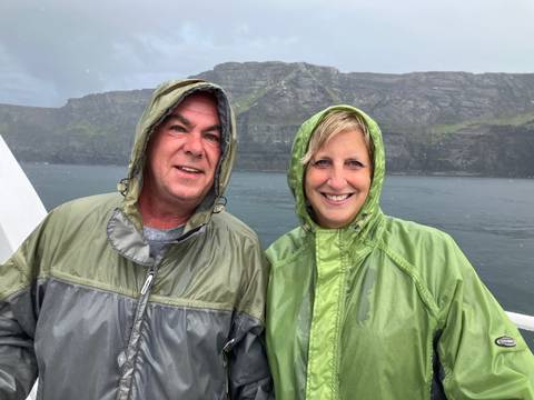 Couple with raincoats in front of the Cliffs of Moher.