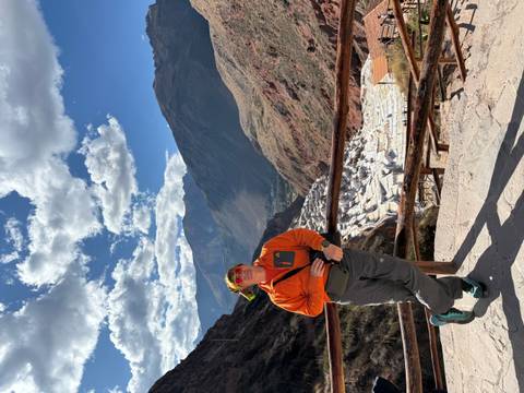 Man posing with the Salt Mines of Maras in the background.