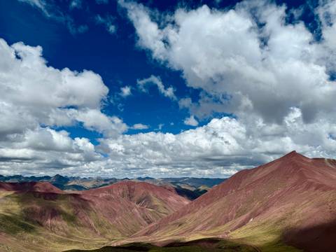 Stunning view of Rainbow Mountain under a vibrant blue sky with clouds.