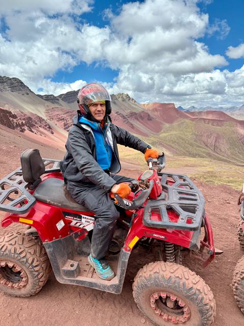 Man on an ATV in front of a mountainous landscape.