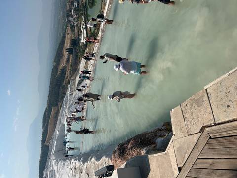       People wading in the travertine terraces of Pamukkale.
  